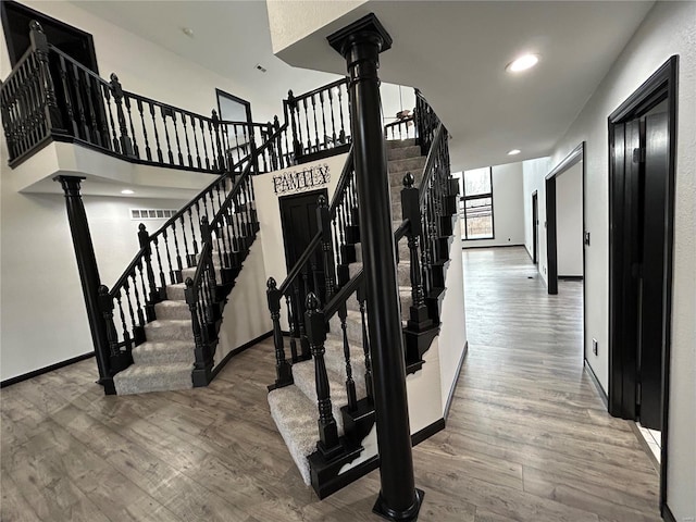 stairway featuring baseboards, recessed lighting, wood finished floors, and ornate columns