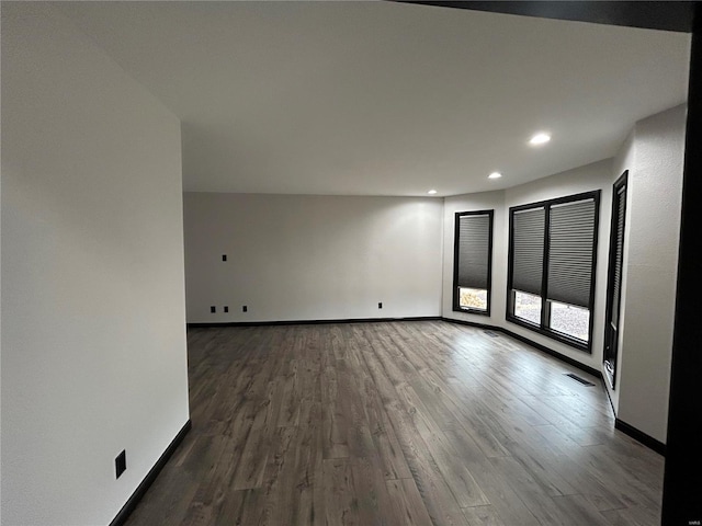 spare room featuring dark wood-type flooring, recessed lighting, visible vents, and baseboards