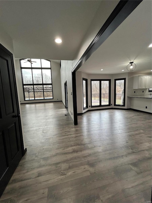 unfurnished living room with dark wood-type flooring, recessed lighting, ceiling fan, and baseboards