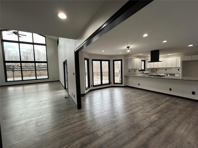 unfurnished living room with recessed lighting, a sink, dark wood finished floors, and baseboards