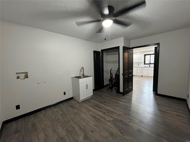 unfurnished room with a textured ceiling, a sink, dark wood finished floors, and baseboards