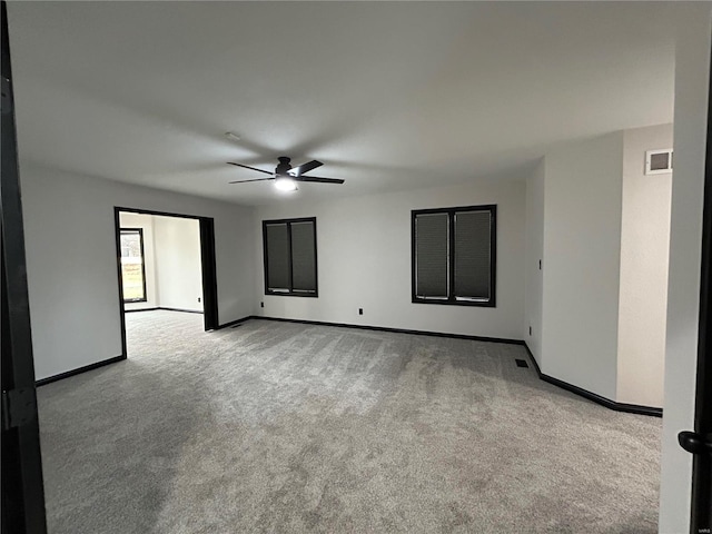 carpeted empty room with ceiling fan, visible vents, and baseboards