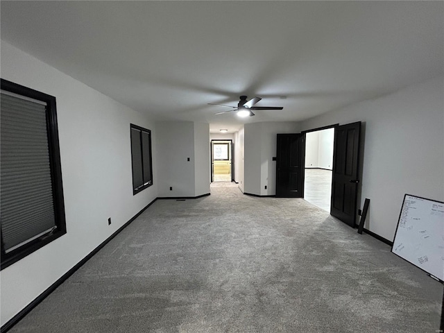 interior space with a ceiling fan, baseboards, and carpet flooring