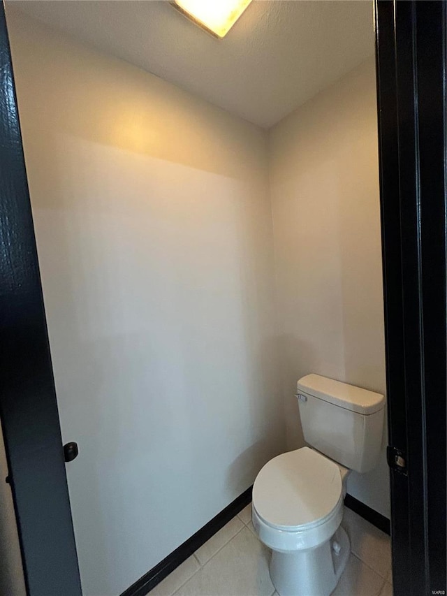 bathroom with tile patterned flooring, baseboards, and toilet