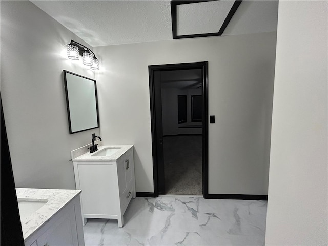 bathroom featuring baseboards, a sink, marble finish floor, a textured ceiling, and two vanities