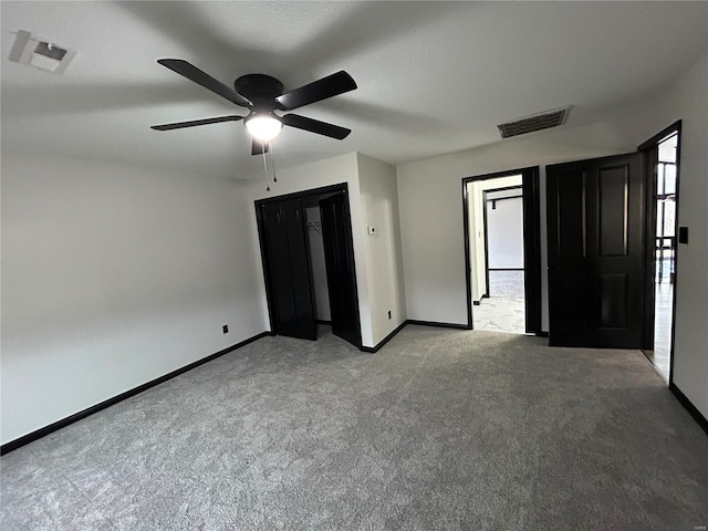 unfurnished bedroom featuring baseboards, a ceiling fan, visible vents, and light colored carpet