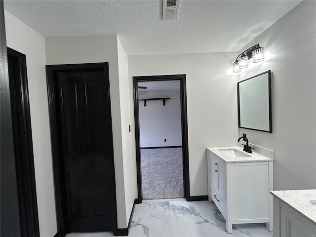 bathroom featuring marble finish floor, visible vents, two vanities, and a sink