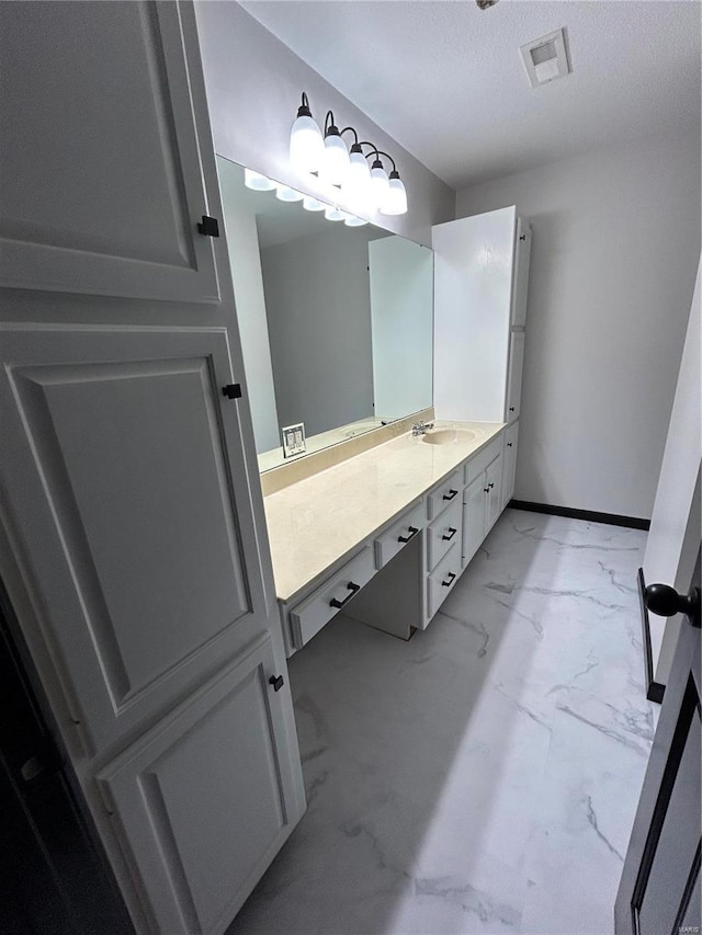 bathroom with a textured ceiling, vanity, visible vents, baseboards, and marble finish floor