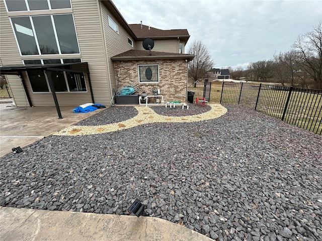 back of property featuring brick siding, fence, and a patio