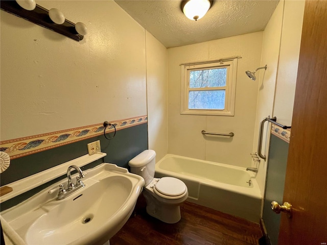 full bathroom with hardwood / wood-style floors, shower / bathing tub combination, sink, toilet, and a textured ceiling