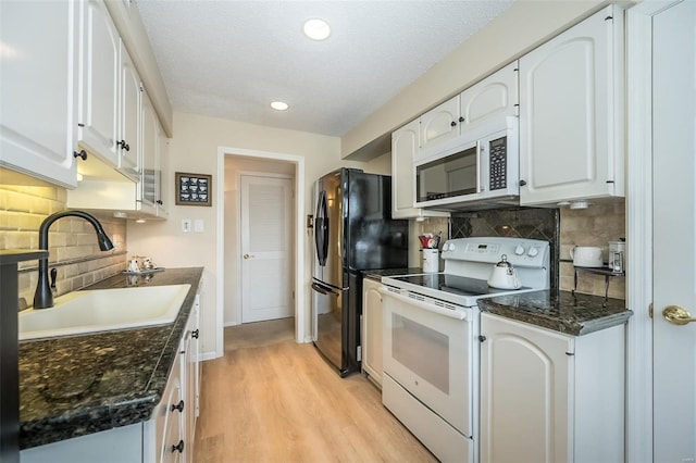 kitchen featuring white appliances, light hardwood / wood-style floors, decorative backsplash, white cabinets, and sink