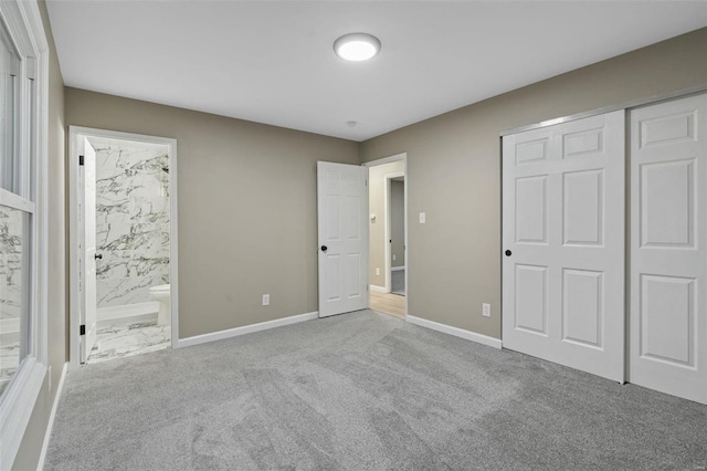 unfurnished bedroom with a closet, ensuite bathroom, and light colored carpet