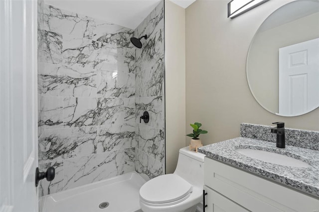 bathroom with toilet, vanity, and a tile shower