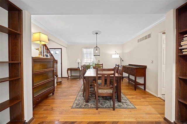 dining room with ornamental molding and light wood-type flooring