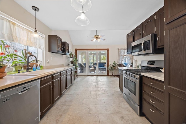 kitchen featuring lofted ceiling, sink, hanging light fixtures, ceiling fan, and stainless steel appliances