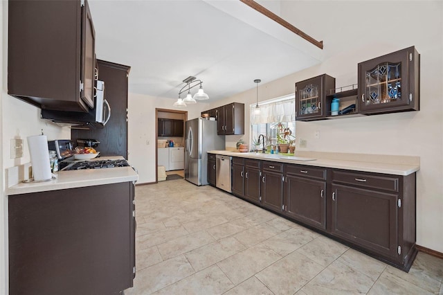 kitchen featuring sink, dark brown cabinets, appliances with stainless steel finishes, pendant lighting, and washing machine and dryer