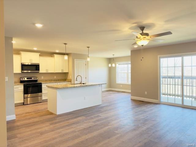 kitchen with white cabinetry, stainless steel appliances, hanging light fixtures, a kitchen island with sink, and ceiling fan