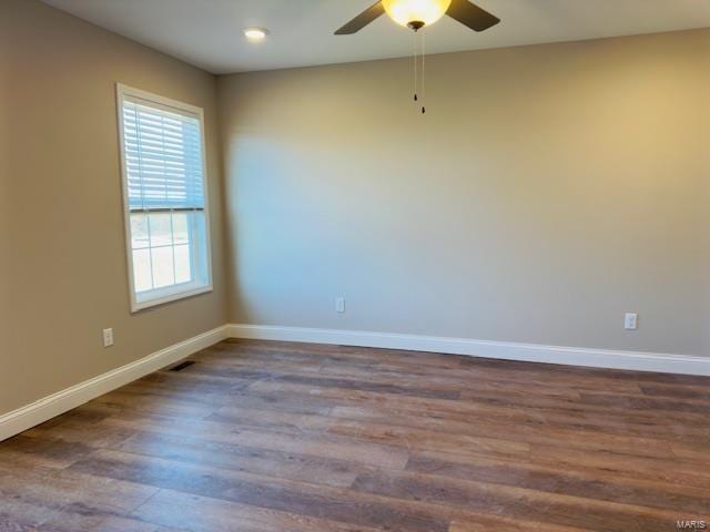 empty room with ceiling fan and dark hardwood / wood-style flooring