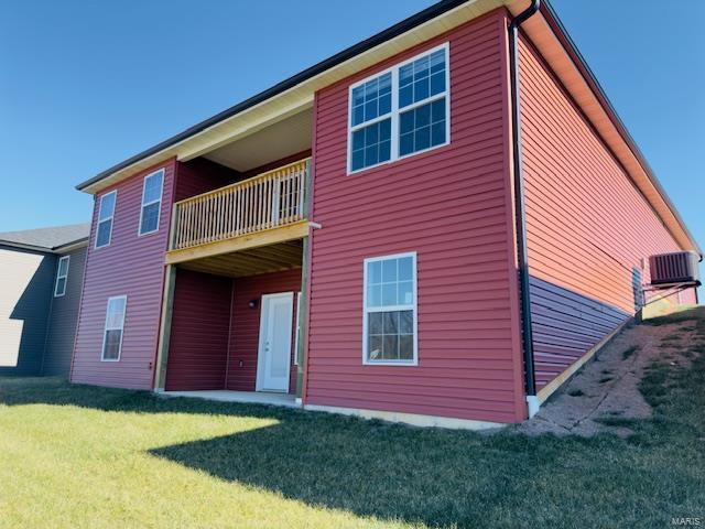 back of house with central AC unit, a balcony, and a yard