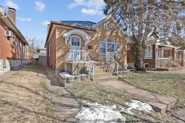 view of front of house with a wall mounted AC and a front lawn