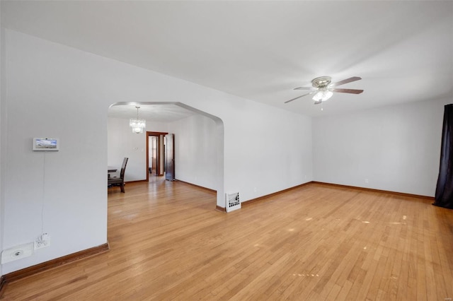 empty room with ceiling fan with notable chandelier and light wood-type flooring