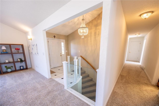 hallway with vaulted ceiling, light colored carpet, and a notable chandelier