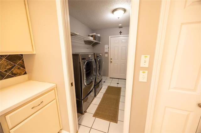 laundry area featuring washer and clothes dryer, a textured ceiling, and light tile patterned floors