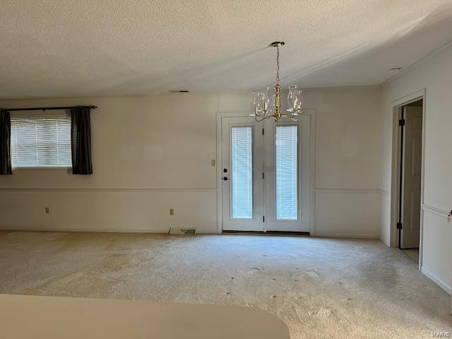 spare room with plenty of natural light, a chandelier, and a textured ceiling