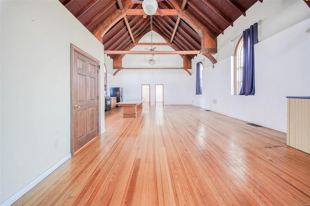 unfurnished living room with wood ceiling, high vaulted ceiling, beamed ceiling, and light wood-type flooring