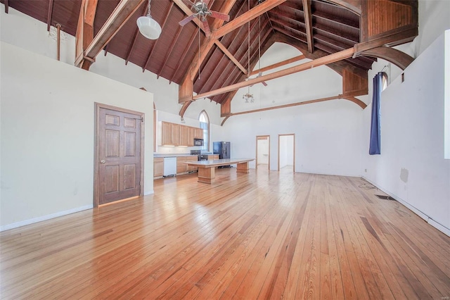 unfurnished living room featuring ceiling fan, beam ceiling, high vaulted ceiling, and light hardwood / wood-style flooring