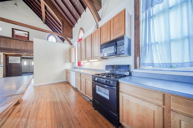 kitchen with light brown cabinetry, black appliances, a high ceiling, and light wood-type flooring