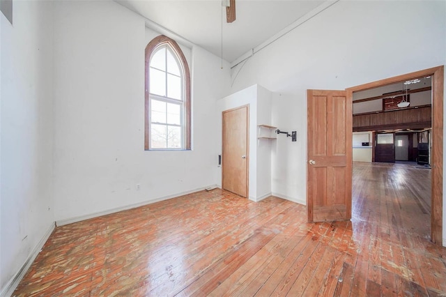 spare room featuring wood-type flooring, ceiling fan, and a high ceiling