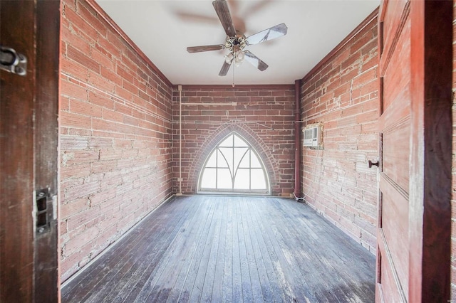 unfurnished room featuring dark hardwood / wood-style flooring, ceiling fan, and brick wall