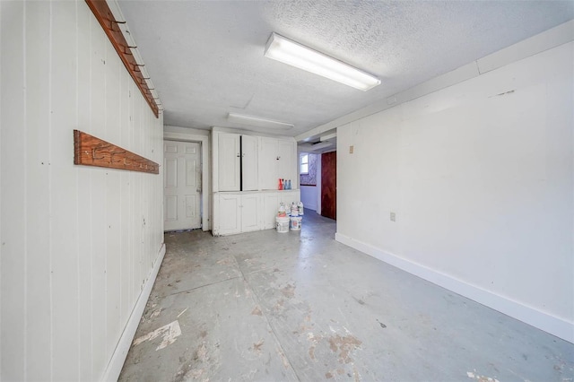 basement with a textured ceiling and wooden walls