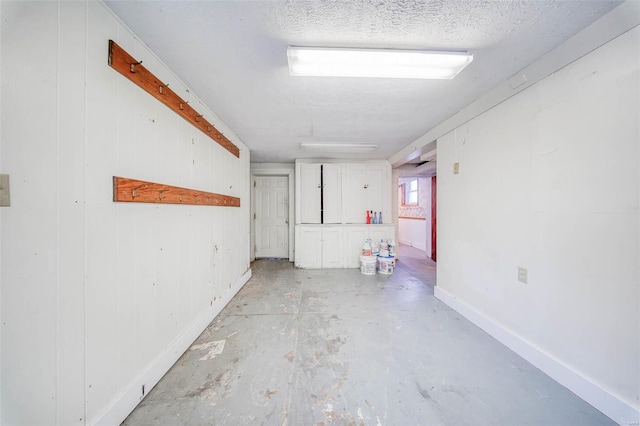 basement featuring wooden walls and a textured ceiling