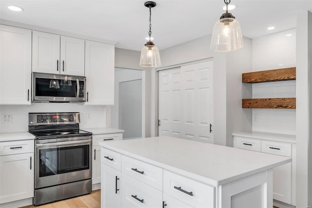 kitchen featuring white cabinetry, stainless steel appliances, a center island, light hardwood / wood-style flooring, and pendant lighting