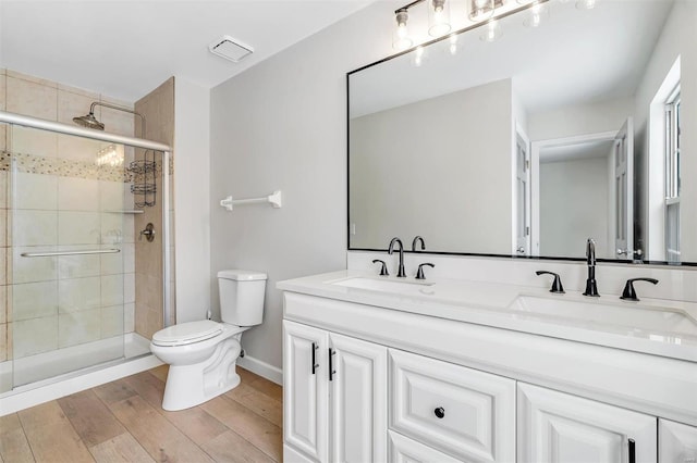 bathroom featuring hardwood / wood-style flooring, an enclosed shower, vanity, and toilet