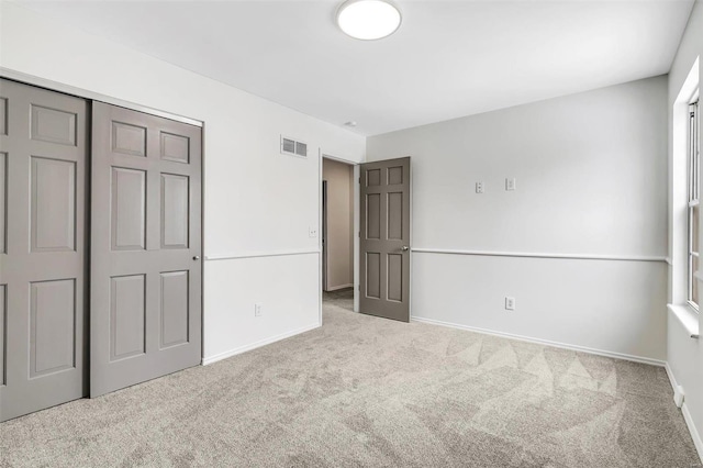 unfurnished bedroom featuring light carpet and a closet