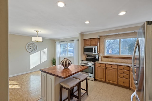 kitchen with butcher block counters, hanging light fixtures, a wealth of natural light, and appliances with stainless steel finishes