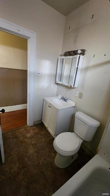 bathroom featuring toilet, a tub to relax in, and vanity