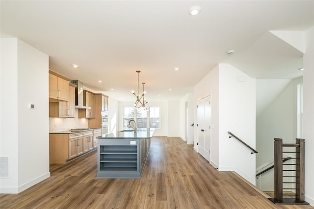 kitchen with stainless steel gas cooktop, sink, dark hardwood / wood-style flooring, an island with sink, and pendant lighting