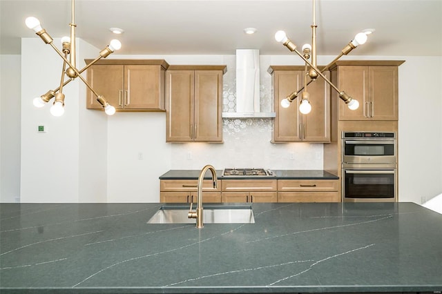 kitchen with wall chimney exhaust hood, sink, tasteful backsplash, appliances with stainless steel finishes, and pendant lighting