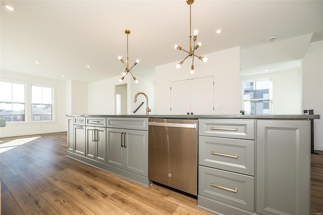 kitchen featuring pendant lighting, gray cabinetry, stainless steel dishwasher, and a center island with sink