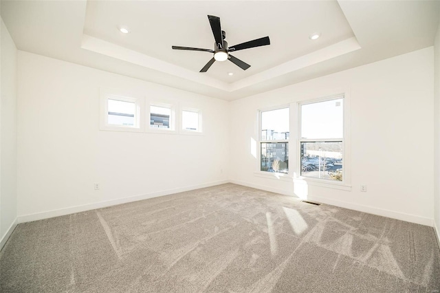 spare room featuring ceiling fan, a tray ceiling, and carpet