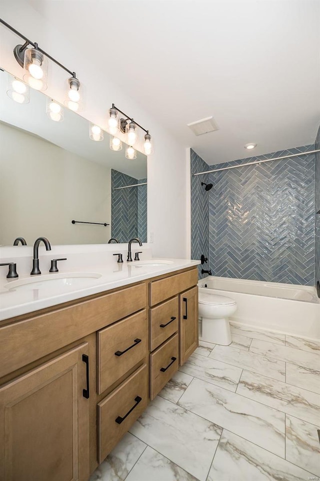 full bathroom featuring tiled shower / bath, vanity, and toilet