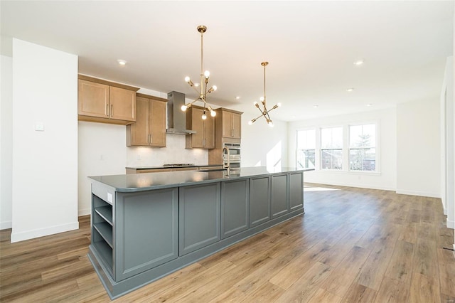 kitchen with tasteful backsplash, a spacious island, hanging light fixtures, a notable chandelier, and wall chimney exhaust hood