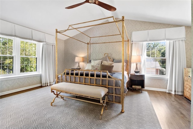 bedroom with ceiling fan, vaulted ceiling, multiple windows, and hardwood / wood-style floors