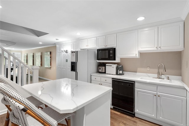 kitchen featuring white cabinetry, light hardwood / wood-style floors, black appliances, crown molding, and sink