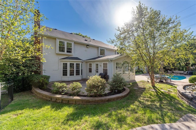 rear view of property featuring a fenced in pool, a patio area, and a yard