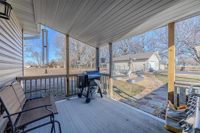 deck featuring a garage, a grill, and an outbuilding